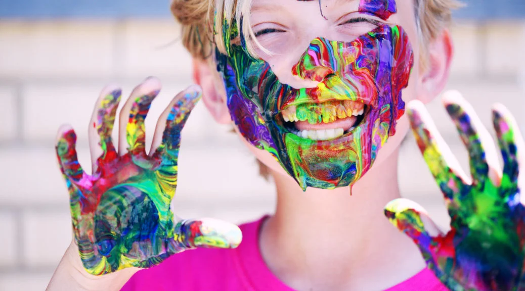 garçon souriant avec peinture sur les mains et le visage